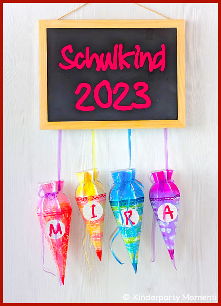 Mini-Schultüten hängen an einer Tafel mit der Aufschrift Schulkind 2023 