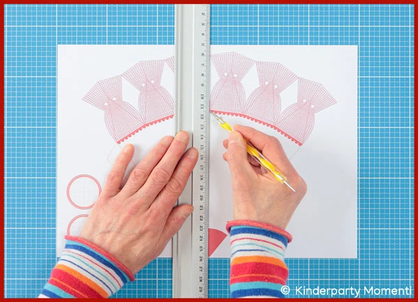 Hände, die mit Prägestift und Lineal die Falzlinien auf einer Schultüten Vorlage nachzeichnen