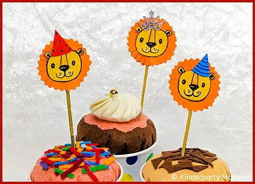 Drei Kuchen mit Löwen-Gesicht-Cake-Toppern, zwei mit Partyhüten und einer mit einer kleinen Krone