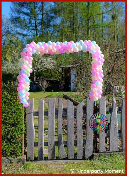 Ballonbogen aus Wasserbomben-Luftballons kleine Luftballons bilden eine Girlande über einem Gartentor aus Holz