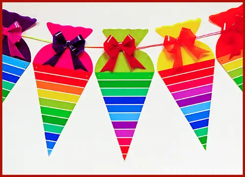 Bunte Wimpelkette aus Zuckertüten mit Regenbogenstreifen und Schleifen in verschiedenen Farben