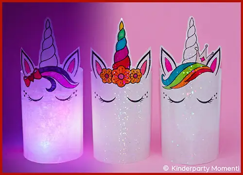 Drei leuchtende Einhorn-Laternen mit geschlossenen Augen, bunten Hörnern und Blumen- beziehungsweise Kronendekorationen vor rosa Hintergrund
