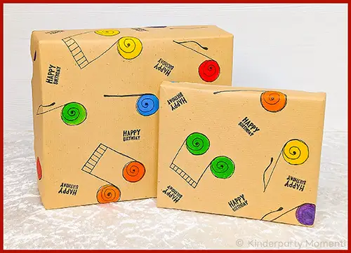 Zwei mit braunem Geschenkpapier umwickelte Geschenke mit bunten selbst gestempelten Noten und dem Schriftzug 'HAPPY BIRTHDAY'