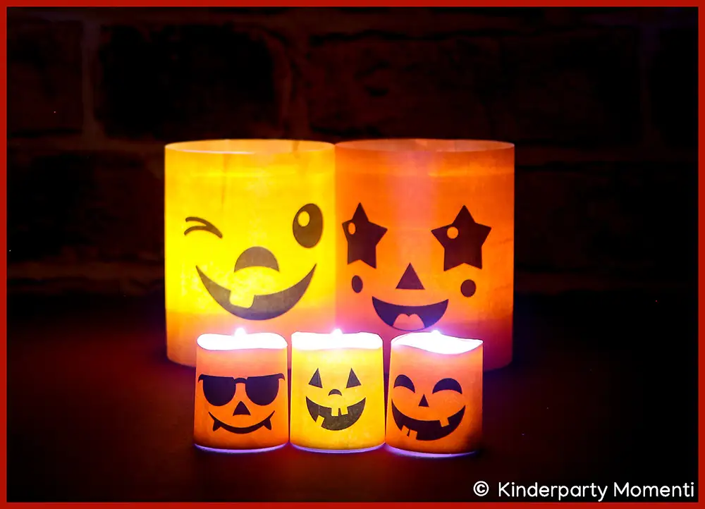 Fünf orangefarbene Halloween Windlichter und LED-Teelichter mit lachenden Gesichtern vor dunklem Hintergrund