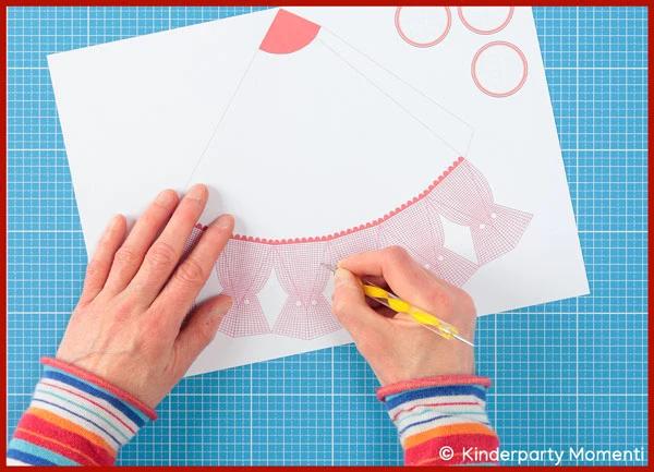 Hände, die mit einem Prägestift die Falzlinien auf einer Schultüten Vorlage nachzeichnen