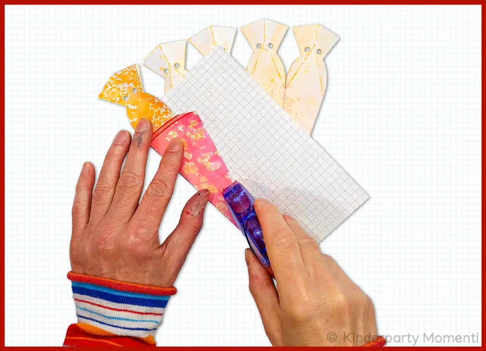 Kleber auf Rand der kleinen Schulüte auftragen Hände tragen mit einem Rollkleber Klebstoff auf den Rand der Mini-Schultüte auf.