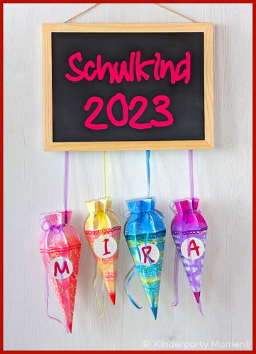 Mini-Schultüten hängen an einer Tafel mit der Aufschrift Schulkind 2023 