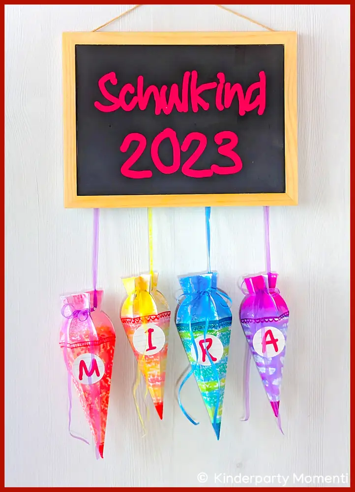 Mini Schultüten mit Name als Einschulungsdeko Mini Schultüten hängen an einer Tafel mit der Aufschrift Schulkind 2023.