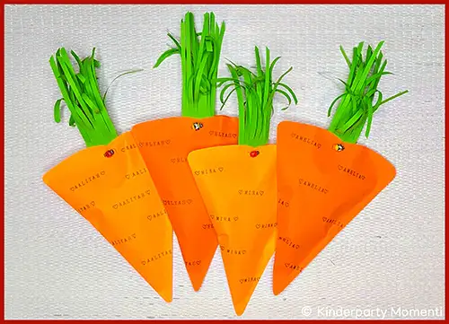 Vier orangefarbene, kegelstumpfförmige Geschenkverpackungen mit grünen Papierstreifen als Karottengrün