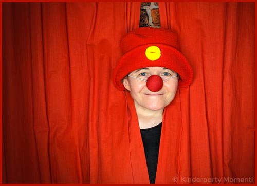 Frau mit roter Clownsnase schaut durch einen Vorhang