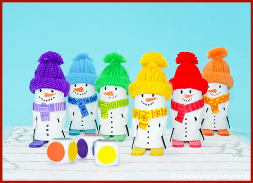 Sechs kleine Schneemänner aus Papier mit bunten Mützen, Schals und Schuhen stehen in einer Reihe vor einem hellblauen Hintergrund