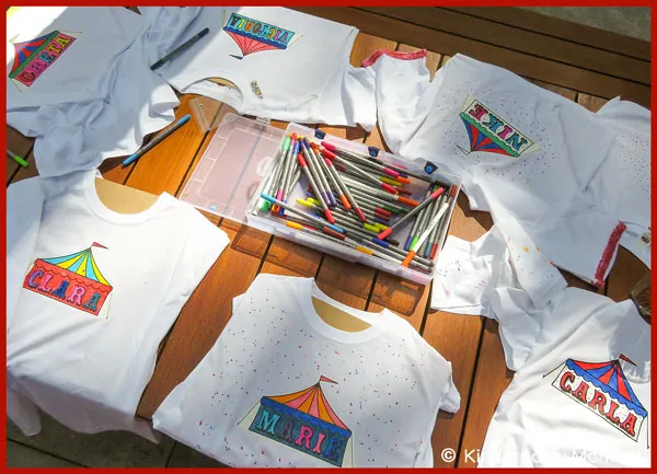 Zirkus T-Shirts bemalen beim Kindergeburtstag auf einem Tisch liegen von Kindern bei einem Zirkus Kindergeburtstag mit bunten Zirkuszelten bemalte T-Shirts und in der Mitte liegen Textilmalstifte