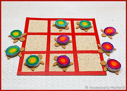 Tic-Tac-Toe-Spiel mit bunten Schildkrötenfiguren auf einem roten Spielfeld mit neun Feldern auf hellem Untergrund
