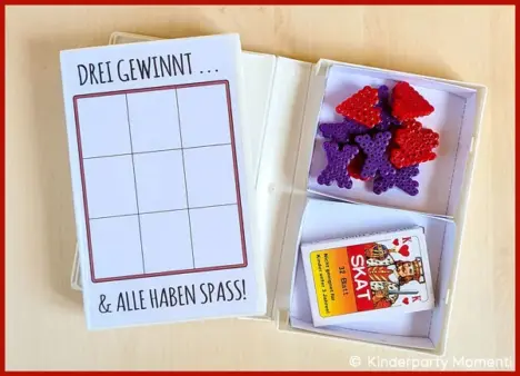 Verschiedene Spiele aufbewahren in VHS-Hüllen Zwei VHS-Hüllen, eine mit eine Tic-Tac-Toe Feld und eine offene in der Spielfiguren und ein Kartenspiel liegen
