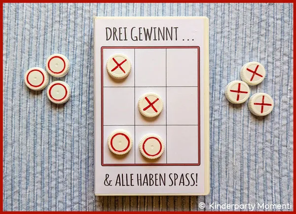 Tic-Tac-Toe Spielen mit Flaschendeckeln auf einem Tisch liegt eine alte VHS Hülle aus der ein Tic-Tac-Toe Spiel gebastelt wurde, sie Spielsteine sind Flaschendeckel