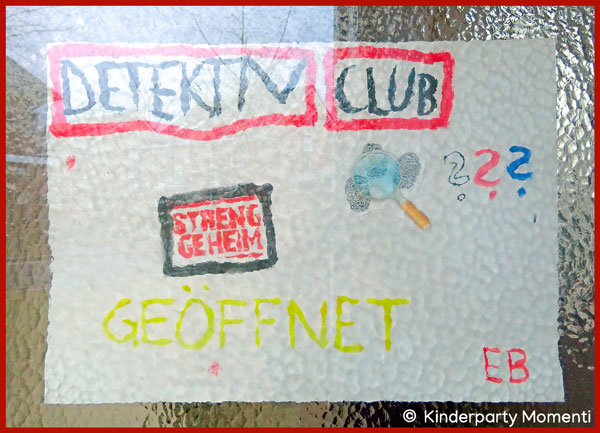 Willkommensschild für Detektivparty hinter der Glasscheibe einer Eingangstür ist ein Kinderbild mit Detektivmotiven zu sehen
