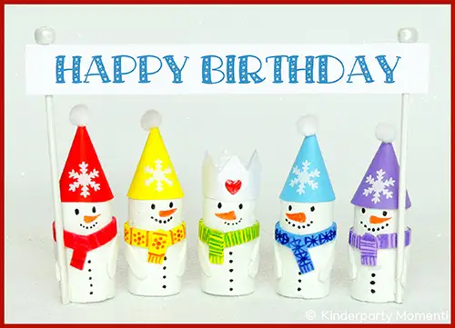 Fünf Schneemänner mit bunten Mützen und Schals halten ein Schild mit der Aufschrift 'HAPPY BIRTHDAY'