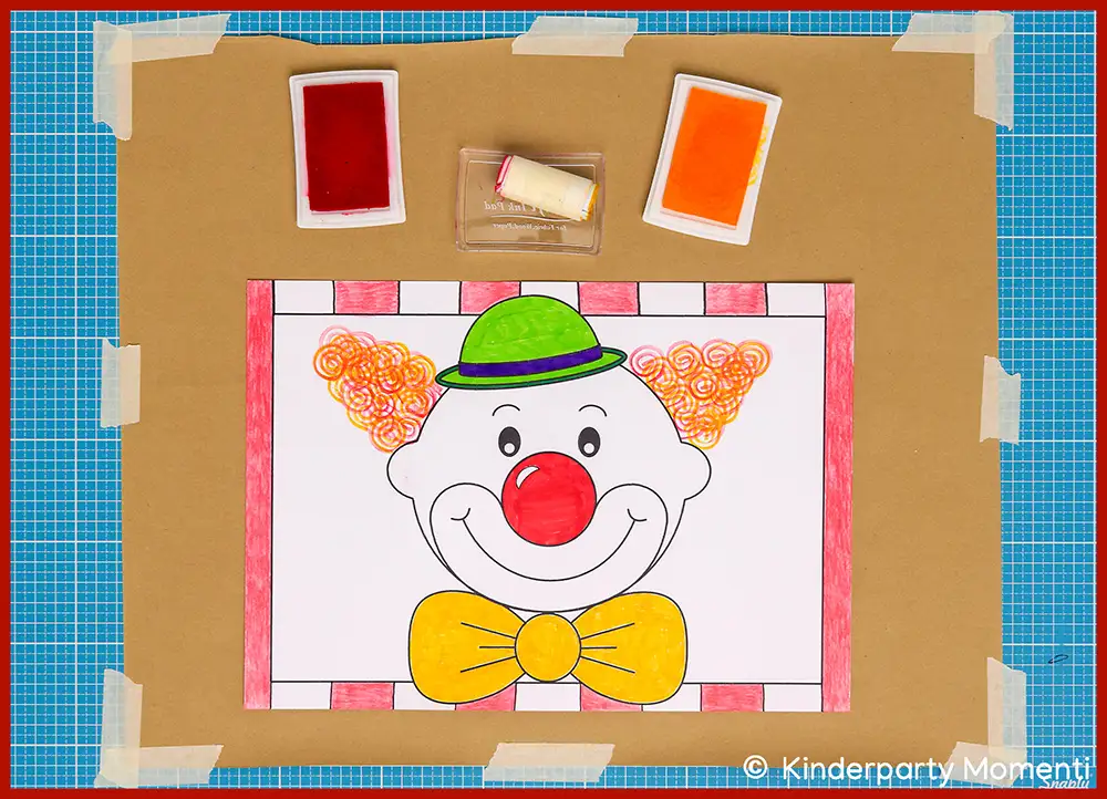 Lachender Clown mit roter Nase, grüner Melone, orangefarbenen Locken und gelber Fliege auf Papier, umgeben von Stempelkissen und Stempelrolle