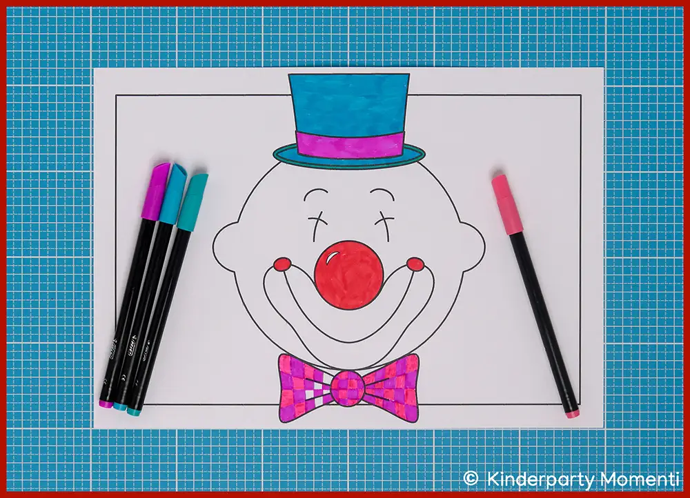 Ausgemaltes Clownsgesicht mit Zylinder und Fliege auf einem karierten Untergrund, daneben liegen bunte Filzstifte