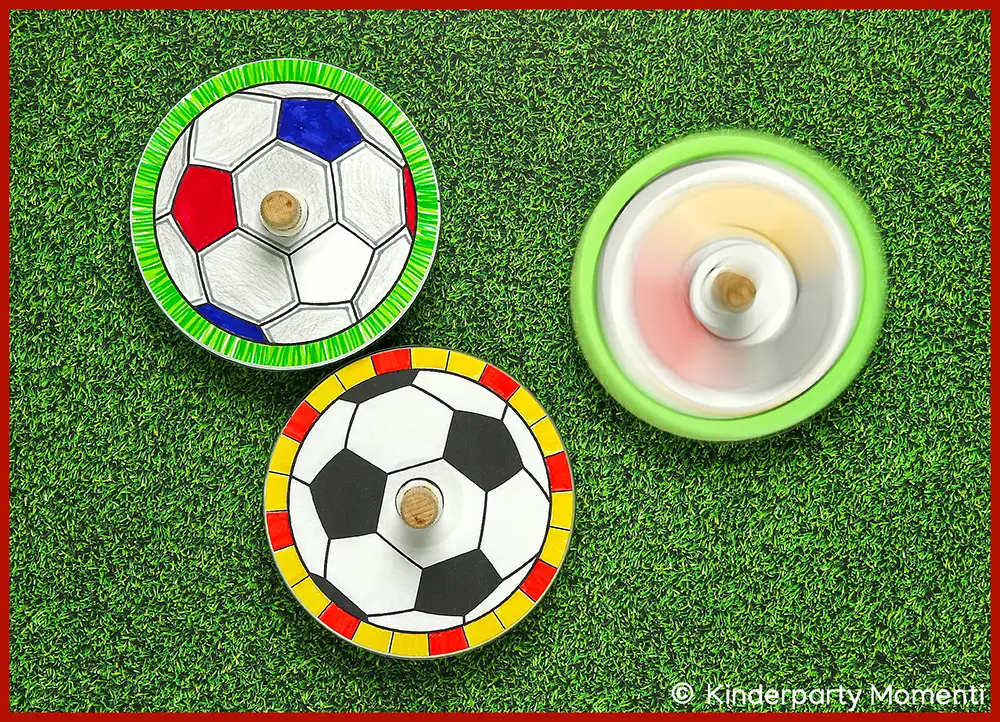 Selbstgebasteltes CD Kreisel Spielzeug mit Fußball Motiven Drei bunte Kreisel mit Fußballmustern, einer davon in Bewegung unscharf