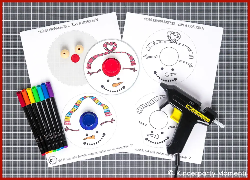 Bastelmaterial und Vorlagen zum Ausdrucken für DIY Kreisel aus CDs Drei ausgedruckte Schneemann-Kreisel-Vorlagen mit bunten Markern, Holzperlen und einer Heißklebepistole auf grauer Bastelmatte