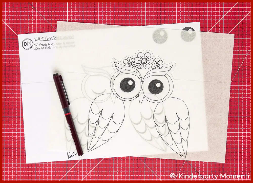 Bild zeigt wie man die Eulen Laternen Vorlage mit eigenen Motiven wie Blumen gestalten kann, die Eulen Vorlage liegt auf einer roten Bastelmatte