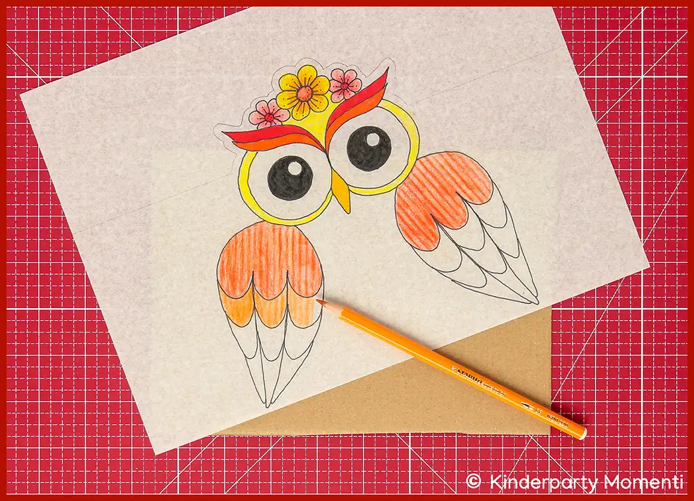 Bild zeigt, wie man mit einem Buntstift auf einer rot-orange bemalte Eulen Laterne eine Struktur malen kann, die ausgedruckte Vorlage liegt auf einer roten Bastelmatte