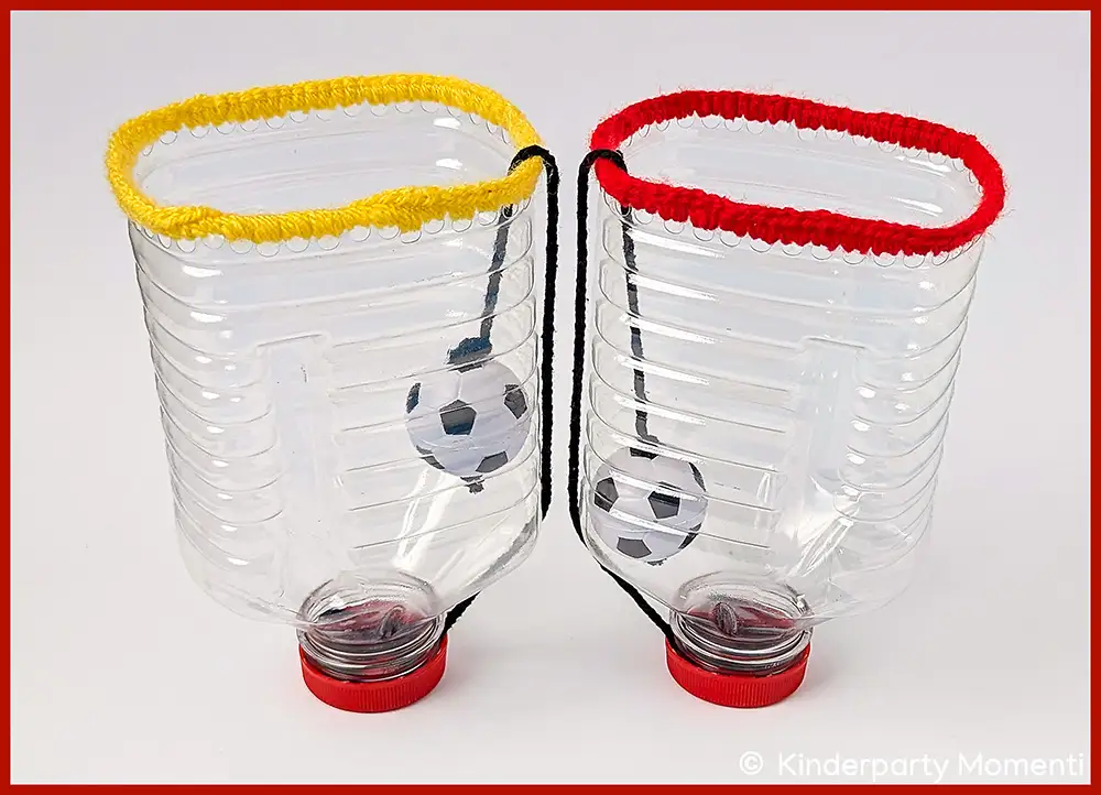 Zwei aus Plastikflaschen gebastelte Fangbecher mit Fußballmotiven und farbigen Randabschlüssen