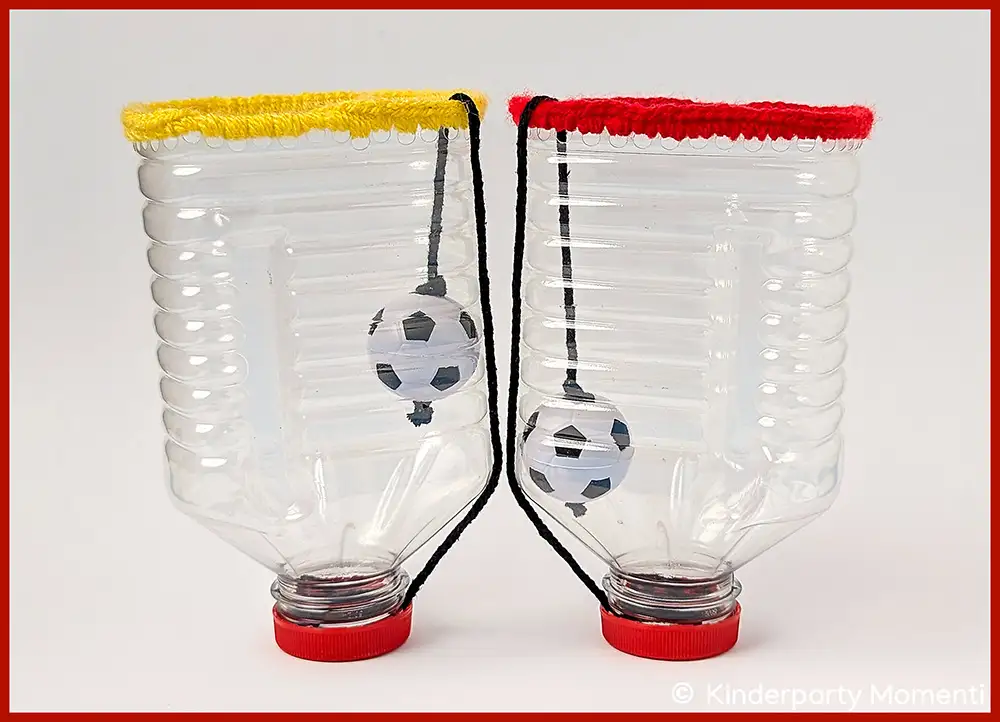Zwei aus Plastikflaschen gebastelte Fangbecher mit Fußballmotiven und farbigen Randabschlüssen