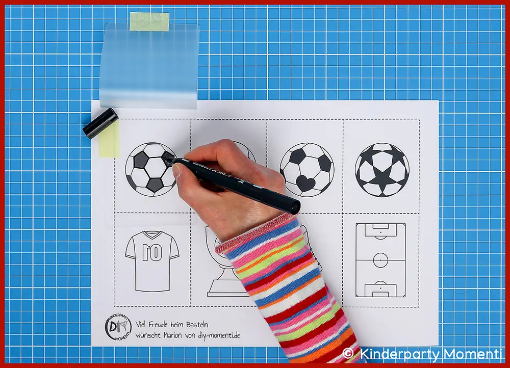 Bastelschritt 2 - Fußball Motive auf Laminierfolie übertragen Hand mit Filzstift zeichnet auf Laminierfolie schwarz-weiße Fußballmotive nach, darunter Fußball, Trikot, Pokal und Spielfeld,