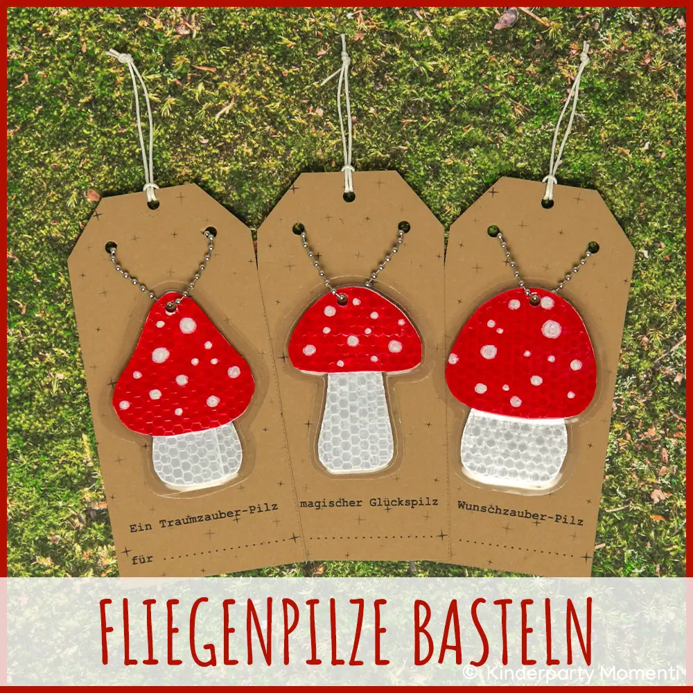 Drei gebastelte Fliegenpilz Anhänger mit roten Kappen und weißen Punkten auf braunen Geschenkanhängern, liegend auf grünem Moos.