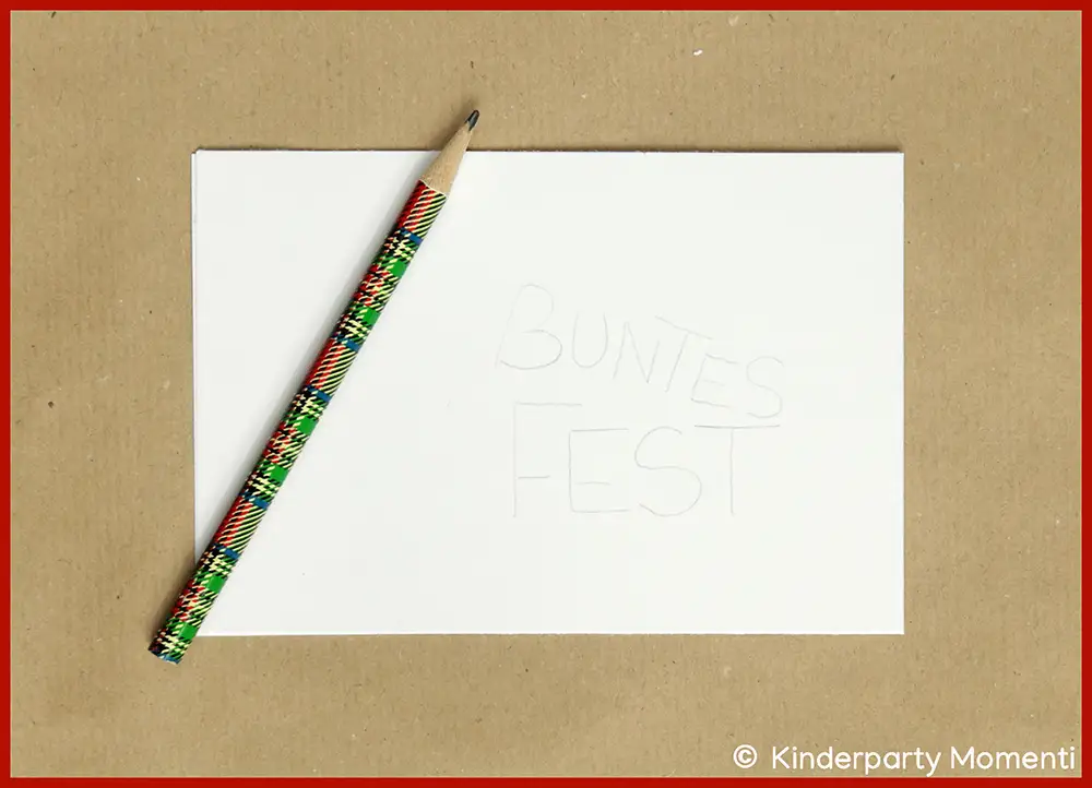 Buntstift liegt auf weißem Blatt mit schwach lesbarer Schrift 'BUNTES FEST'.