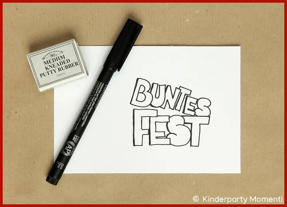 Schwarzer Filzstift und Radiergummi neben eineVorlage für eine Weihnachtskarte mit handgeschriebenem Text 'BUNTES FEST' in Großbuchstaben.