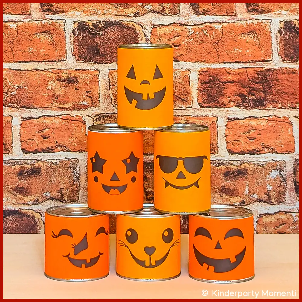 DIY Dosenwerfen für Halloween vor dem Wurf Sechs Dosen mit orangefarbenen Halloween-Gesichtern als Dosenwurfspiel vor roter Backsteinwand,