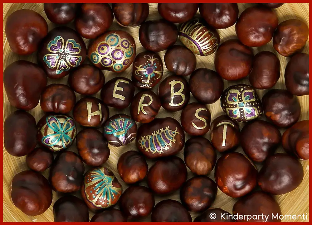 Kastanien mit herbstlichen Mustern und Buchstaben, die das Wort 'HERBST' bilden, in einer Holzschale