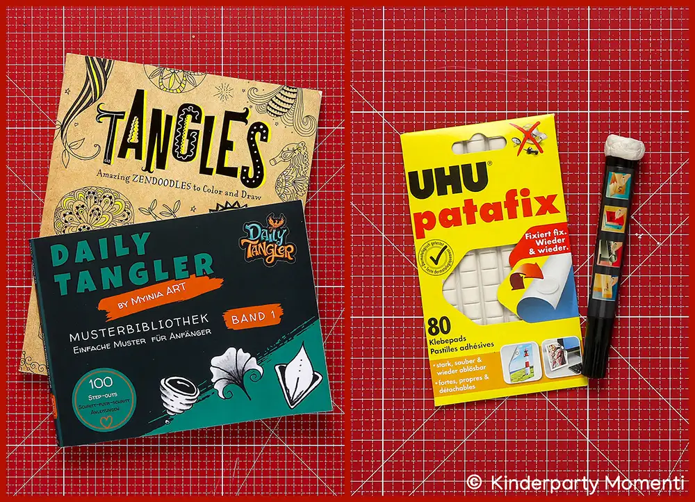 Zwei Bücher mit Mustern und ein Paket UHU patafix Klebepads neben einem Stift Knetkleber Spitze auf roter Bastelmatte