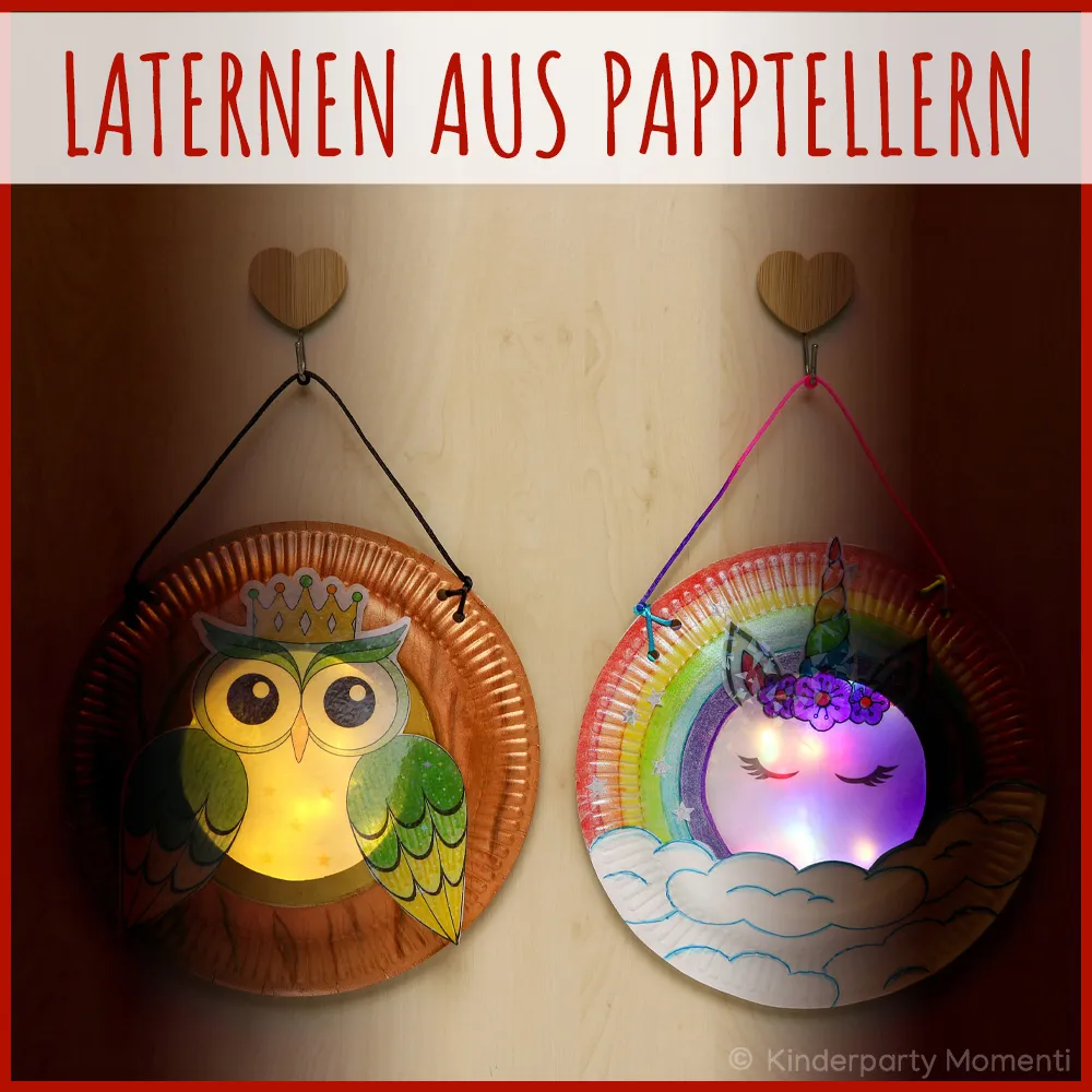 Zwei Laternen aus Papptellern, eine mit Eulenmotiv und eine mit Einhornmotiv, beide beleuchtet und an herzförmigen Haken aufgehängt