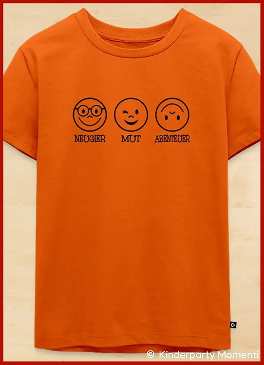 Orangfarbenes Kinder-T-Shirt mit drei schwarzen Smiley-Gesichtern und den Worten 'Neugier Mut Abenteuer' darunter
