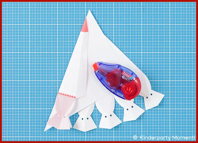 08 - Anleitung kleine Schultüten basteln - Vorlage zusammen kleben Auf einer Bastelmatte liegt die Bastelvorlage für eine kleine Schultüte und ein Kleberoller.