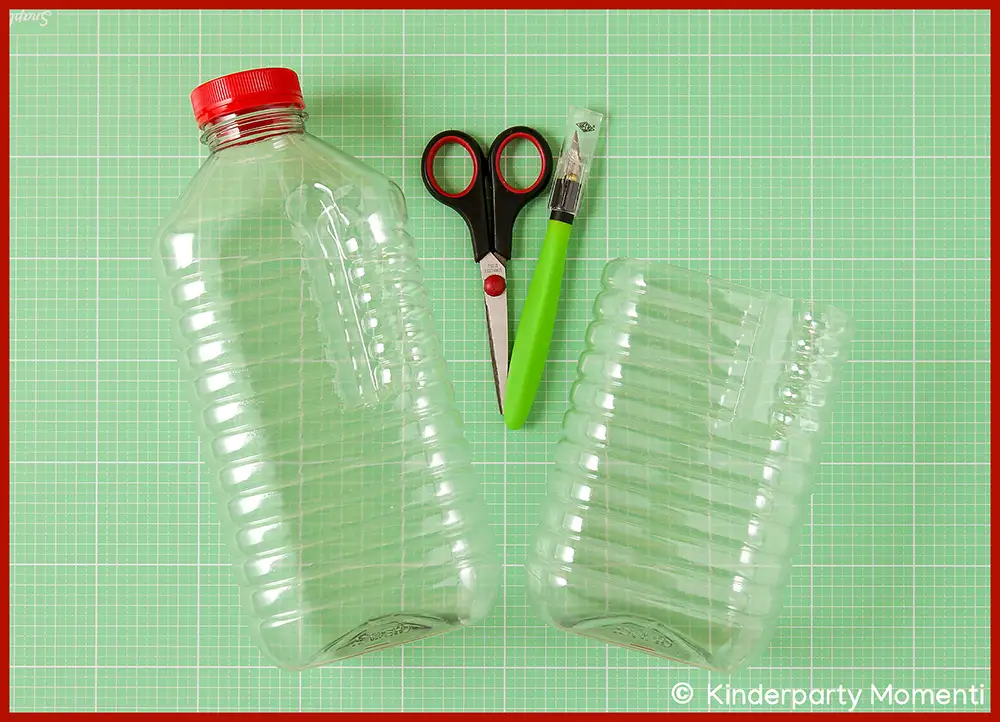 Zwei durchsichtige Plastikflaschen, eine mit rotem Deckel, daneben eine Schere mit schwarzen Griffen und ein grüner Cutter auf grüner Bastelmatte