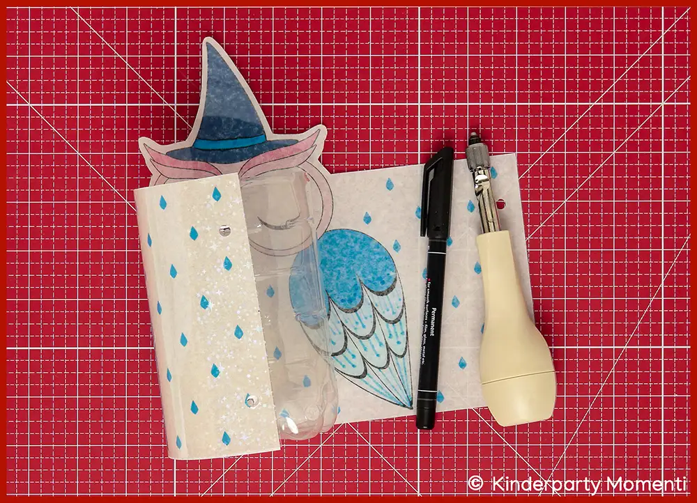 Bild zeigt wie eine zugeschnittene PET Flasche für eine Eulenlaterne mit einem Drehlocher gelocht werden soll, die Eulen Vorlage liegt auf einer roten Bastelmatte