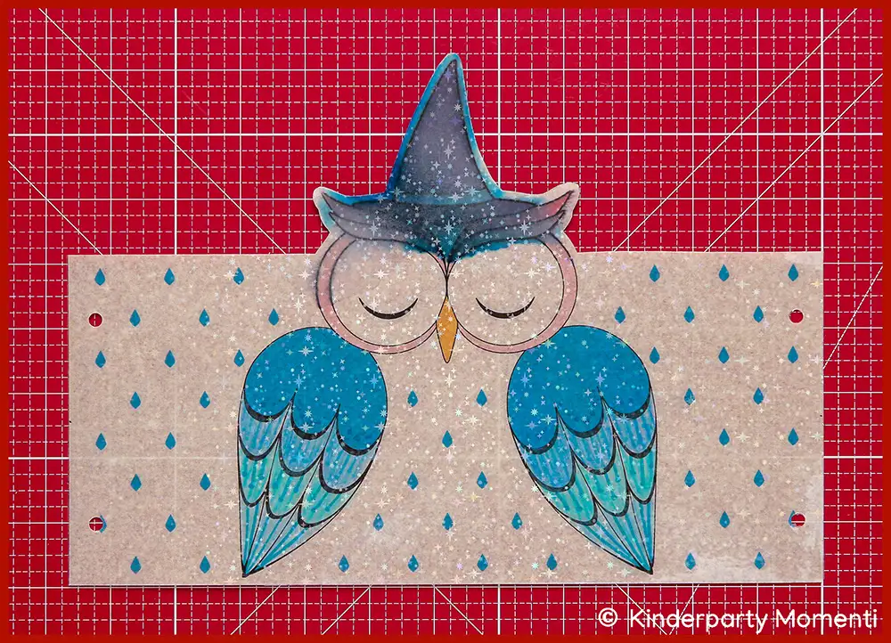 Blau bemalte Bastelvorlage für eine Eulenlaterne mit verlaufenen Farben, die Laternen Vorlage liegt auf einer roten Bastelmatte