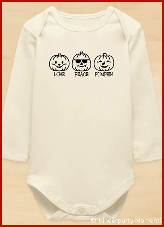 Hellfarbiger Baby-Body mit drei schwarz-weißen Kürbisgesichtern und dem Text 'Love  Peace Pumpkin'