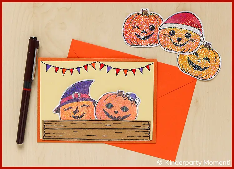 Halloween Karte und lustige Sticker zum dekorieren Karte mit zwei lachenden Kürbissen, einer mit Hexenhut, in einer gemalten Gemüsekiste vor Wimpelkette, daneben drei Kürbissticker mit verschiedenen Gesichtsausdrücken auf hellem Untergrund