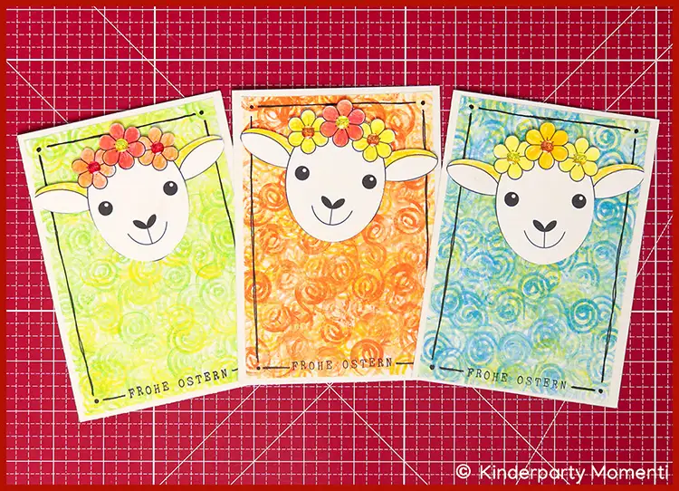 Drei bunte Osterkarten mit Schafgesichtern mit Blumenkränzen auf gemustertem Hintergrund, darunter der Schriftzug 'FROHE OSTERN'