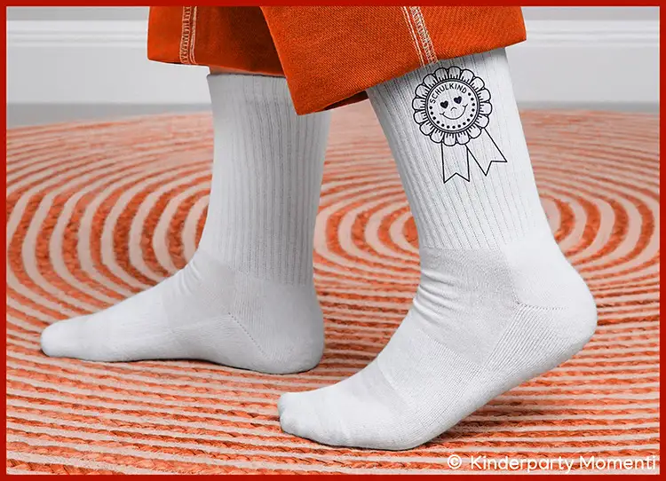 Schulkind Socken als Schulstart Geschenk Weiße Socken mit geripptem Muster und einem schwarz-weißen Aufdruck einer Medaille mit der Aufschrift 'SCHULKIND' an den Knöcheln