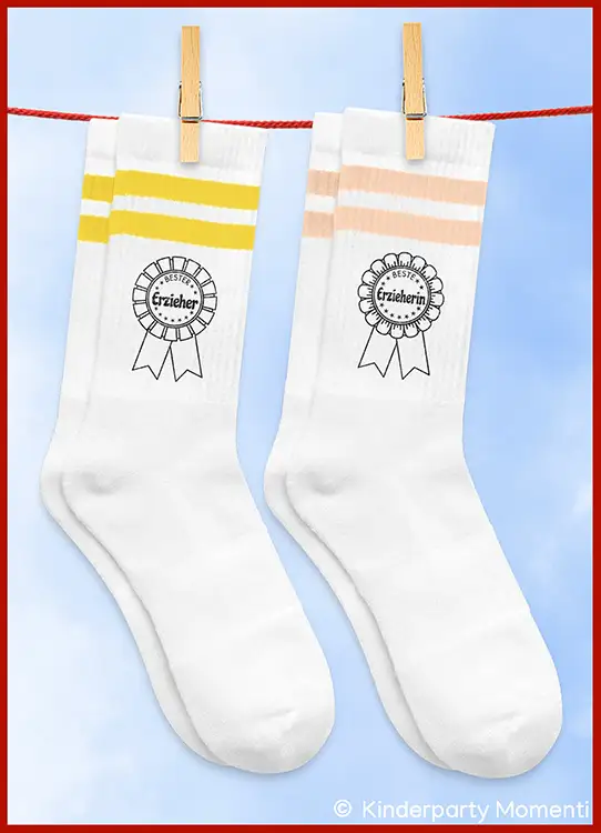 Zwei weiße Socken mit je zwei farbigen Streifen oben, eine gelb, eine rosa, beide mit einem Aufdruck einer Rosette und dem Schriftzug 'Bester Erzieher' und 'Beste Erzieherin'