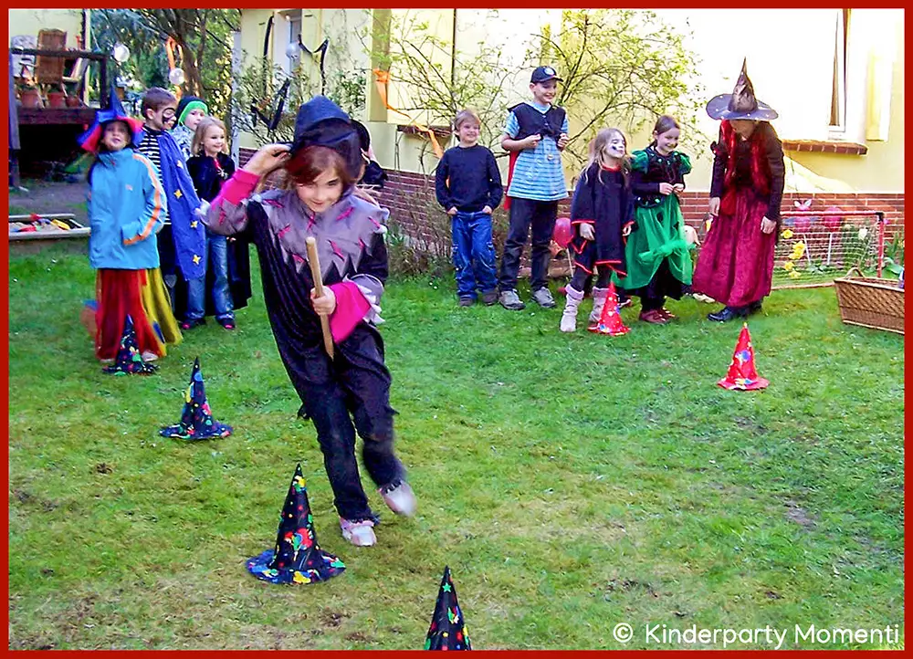 Staffelspiele mit Hexenbesen für Halloween Hexenfest & Hexen Kindergeburtstag Kinder in Zauberer- und Hexen-Kostümen spielen im Garten ein Staffelspiel mit Hexenbesen und laufen dabei um Pylonen, die aussehen wie Hexenhüte