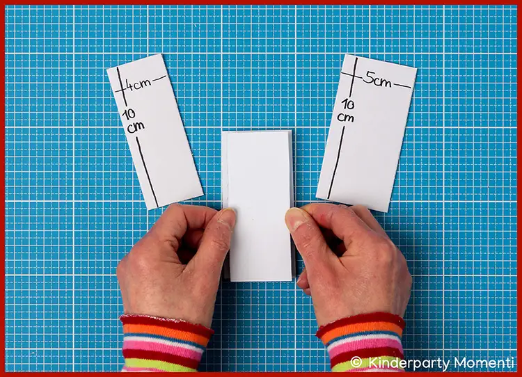 Hände kleben Moosgummi für Stempel zusammen daneben passende Moosgummi Streifen, beschriftet mit '4cm 10cm' und '5cm 10cm'
