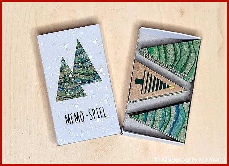 Offenes Memo-Spiel mit Karten in Tannenbaumform und einer Spielschachtel mit Tannenbaum-Motiv